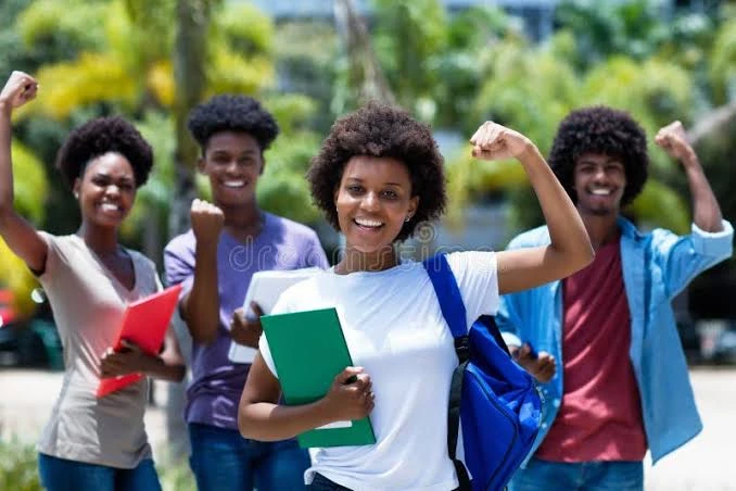 Four Kingdom Foundation College students celebrating outdoors with books